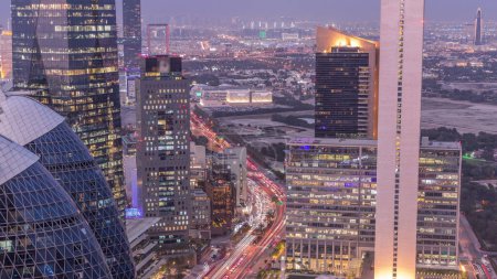 Téléchargez les photos : Vue aérienne des immeubles de grande hauteur sur la route achalandée de Dubaï timelapse de transition de jour à nuit, Émirats arabes unis. Des gratte-ciels de bureaux éclairés dans la place financière internationale d'en haut - en image libre de droit