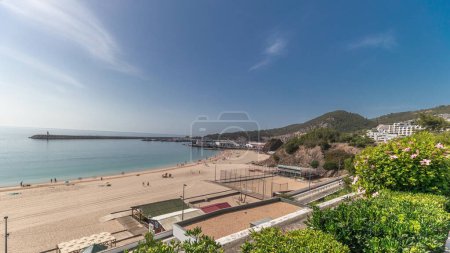 Téléchargez les photos : Panorama showing green garden and the coastline of the village of Sesimbra timelapse, in the middle of the Atlantic Ocean. View of the beach and waterfront with lawn from above. Portugal - en image libre de droit