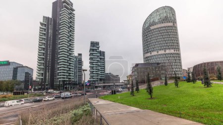 Téléchargez les photos : Panorama showing skyscrapers and biblioteca from park with green lawn timelapse. Located between Piazza Gae Aulenti and the Isola district. Traffic on the road intersection. Milan. Italy - en image libre de droit