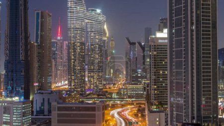 Téléchargez les photos : Tours futuristes et gratte-ciel avec circulation dans les rues de Dubaï Centre-ville et quartier financier après le coucher du soleil. Urbain ville skyline aérien jour à nuit transition timelapse d'en haut - en image libre de droit