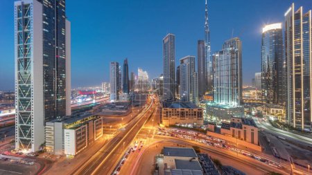 Foto de Vista panorámica aérea del horizonte del centro de Dubái con muchas torres de día a noche timelapse transición. Área de negocios en la ciudad urbana inteligente. Rascacielos y edificios de gran altura desde arriba después del atardecer, EAU. - Imagen libre de derechos