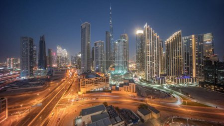 Téléchargez les photos : Vue aérienne panoramique de Dubaï Skyline du centre-ville avec de nombreuses tours timelapse de transition de jour à nuit. Zone d'affaires trafic routier achalandé. gratte-ciel et gratte-ciel d'en haut après le coucher du soleil, Émirats arabes unis - en image libre de droit
