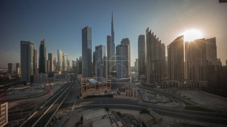 Photo for Aerial view of Dubai Downtown skyline during sunrise with many towers timelapse. Sun beams between skyscrapers and high-rise buildings from above, UAE. Business area in smart urban city. - Royalty Free Image