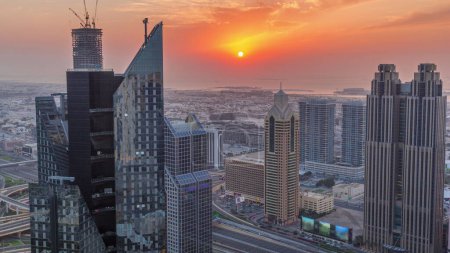 Téléchargez les photos : Bâtiments de grande hauteur sur Sheikh Zayed Road à Dubaï timelapse aérien, EAU. Gratte-ciel dans le quartier financier international d'en haut pendant le coucher du soleil. Maisons de promenade en ville et villas sur un fond - en image libre de droit