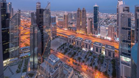 Téléchargez les photos : Bâtiments de grande hauteur sur Sheikh Zayed Road à Dubaï transition aérienne nuit au jour timelapse panoramique, EAU. Gratte-ciels dans le quartier financier d'en haut. Maisons de ville et villas en arrière-plan - en image libre de droit