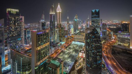 Téléchargez les photos : Panorama montrant la vue d'horizon des immeubles de grande hauteur sur Sheikh Zayed Road à Dubaï timelapse de nuit aérienne, Émirats arabes unis. Des gratte-ciel éclairés de la place financière internationale d'en haut - en image libre de droit