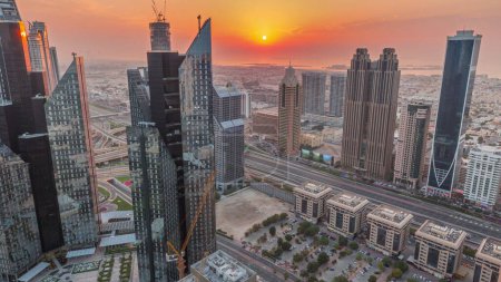 Photo for High-rise buildings on Sheikh Zayed Road in Dubai aerial timelapse, UAE. Skyscrapers in international financial district from above during sunset. City walk houses and villas on background. Orange sky - Royalty Free Image
