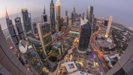 Foto de Skyline panorama de los edificios de gran altura en Sheikh Zayed Road en Dubai día aéreo a la noche timelapse transición, Emiratos Árabes Unidos. Rascacielos iluminados en el Centro Financiero Internacional desde arriba - Imagen libre de derechos