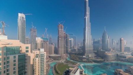 Téléchargez les photos : Vue aérienne de la ville de Dubaï tôt le matin pendant le temps de brouillard. Lever de soleil à horizon futuriste de la ville avec des gratte-ciel et des tours d'en haut. Soleil réfléchi par la surface du verre avec des rayons de lumière - en image libre de droit
