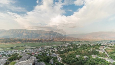 Téléchargez les photos : Panorama montrant la ville de Gjirokastra du point de vue de la forteresse du château ottoman de Gjirokaster timelapse. Albanie vue aérienne sur la vallée et les montagnes pendant l'heure du coucher du soleil - en image libre de droit