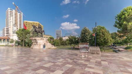 Téléchargez les photos : Panorama montrant le mémorial de Skanderbeg et la mosquée Ethem Bey avec théâtre sur la place principale de Tirana timelapse, Albanie. Arbres verts dans un parc et gratte-ciel autour - en image libre de droit