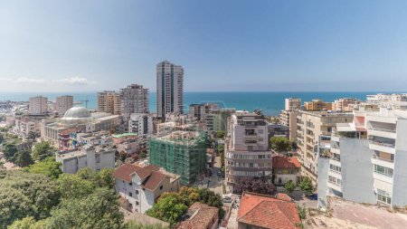 Photo for Panorama showing aerial view of city centre (old town) and the harbour of Durres timelapse from viewpoint, Albania. Many houses with green trees from above with clouds on she sky - Royalty Free Image