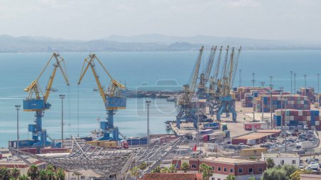 Photo for Aerial view from above to the port of Durres in the Adriatic Sea timelapse. A platform for containers surrounded by tower cranes for unloading. In the port there are many cargo trucks moving around - Royalty Free Image