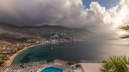 Photo for Panorama showing Amorgos island aerial timelapse from above with clouds before sunset. Traditional Greece - white houses on hills and turquoise sea, Cyclades - Royalty Free Image