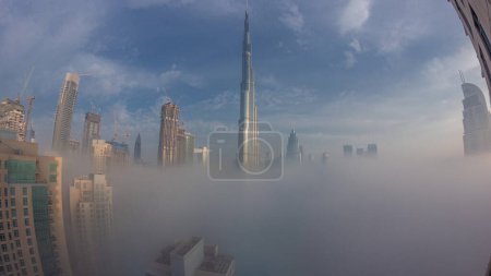Foto de Vista aérea de la ciudad de Dubai temprano en la mañana durante la noche de niebla al timelapse de transición del día. skyline futurista de la ciudad con rascacielos y torres durante el amanecer desde arriba - Imagen libre de derechos