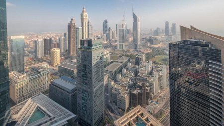 Photo for Panorama of futuristic skyscrapers in financial district business center in Dubai on Sheikh Zayed road night to day transition timelapse. Aerial view from above with illuminated towers before sunrise - Royalty Free Image