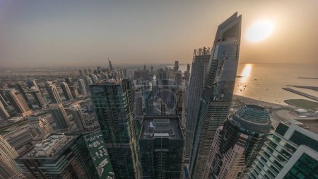 Photo for Skyline panoramic view of Dubai Marina showing an artificial canal surrounded by skyscrapers along shoreline in morning fog aerial timelapse. Floating yachts and boats. DUBAI, UAE - Royalty Free Image