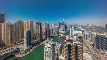 Téléchargez les photos : Panorama de divers gratte-ciel dans le plus haut quartier résidentiel de Dubai Marina timelapse aérien pendant toute la journée avec canal artificiel. De nombreux yachts et tours avec des ombres se déplaçant rapidement - en image libre de droit