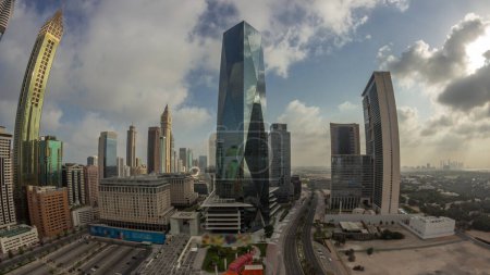 Foto de Panorama del distrito financiero internacional de Dubai. Vista aérea de las torres de oficinas de negocios durante el amanecer. Rascacielos iluminados con hoteles y centros comerciales cerca del centro - Imagen libre de derechos