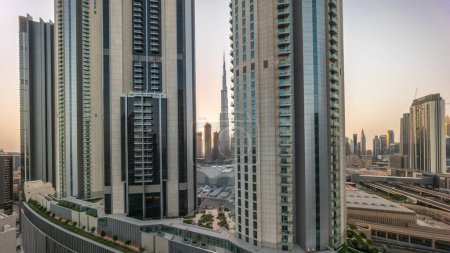Foto de Los rascacielos más altos después del amanecer en el centro de Dubái se encuentran en la calle Boulevard, cerca del centro comercial Timelapse aéreo durante todo el día. Zona de paseo con jardines en la azotea - Imagen libre de derechos