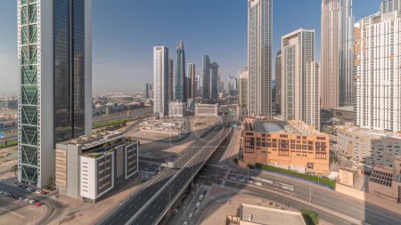 Foto de Vista aérea del horizonte del centro de Dubái con muchas torres timelapse. Tráfico ocupado en la intersección con paso elevado. Sombras en movimiento en el área de negocios. Rascacielos y edificios de gran altura desde arriba, Emiratos Árabes Unidos. - Imagen libre de derechos