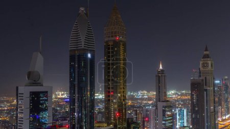 Téléchargez les photos : Vue aérienne des immeubles de grande hauteur sur Sheikh Zayed Road à Dubaï pendant toute la nuit timelapse, EAU. Des gratte-ciel éclairés de la place financière internationale d'en haut avec des lumières éteintes - en image libre de droit