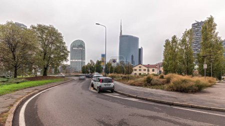 Photo for Panorama showing skyscrapers and towers from park with autumn trees and green lawn timelapse. Located between Piazza Gae Aulenti and the Isola district. Traffic on a road. Milan. Italy - Royalty Free Image