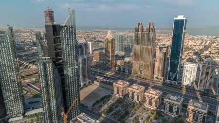 Téléchargez les photos : Bâtiments de grande hauteur sur Sheikh Zayed Road à Dubaï timelapse du matin, Émirats arabes unis. Gratte-ciel dans le quartier financier international d'en haut pendant le lever du soleil. Maisons de ville et villas en arrière-plan - en image libre de droit