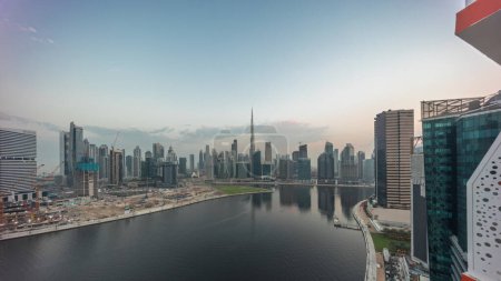 Foto de Panorama aéreo de Dubai Business Bay y Downtown con los diversos rascacielos y torres a lo largo de la costa en el canal noche a día timelapse transición. Lugar de construcción con grúas antes del amanecer - Imagen libre de derechos