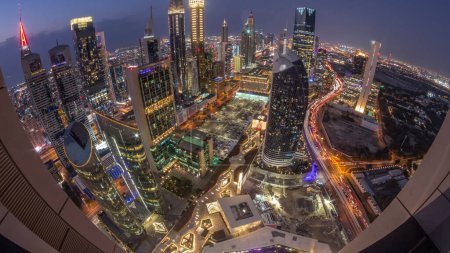 Téléchargez les photos : Skyline panorama des immeubles de grande hauteur sur Sheikh Zayed Road à Dubaï passage aérien du jour à la nuit timelapse, EAU. Des gratte-ciel éclairés de la place financière internationale d'en haut - en image libre de droit
