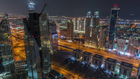 Photo for High-rise buildings on Sheikh Zayed Road in Dubai aerial during all night timelapse, UAE. Skyscrapers of financial district from above. City walk houses on a background. Illumination turning off - Royalty Free Image