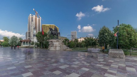 Foto de Panorama que muestra el monumento Skanderbeg y la mezquita Ethem Bey con teatro en la plaza principal en Tirana timelapse, Albania. Árboles verdes en un parque y rascacielos alrededor - Imagen libre de derechos