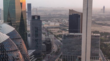Téléchargez les photos : Vue aérienne des immeubles de grande hauteur sur la route courbée de Dubaï, de nuit aérienne à jour timelapse de transition, Émirats arabes unis. gratte-ciel de bureau dans la place financière internationale d'en haut avant le lever du soleil - en image libre de droit