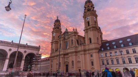 Photo for The Theatine Church of St. Cajetan (Theatinerkirche St. Kajetan) timelapse during sunset. A domed baroque Catholic church with striking yellow facade and ornate white stucco interior. Munich, Germany - Royalty Free Image