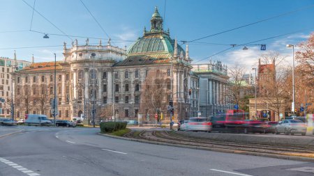 Foto de Vista exterior del Palacio de Justicia en el timelapse de Karlsplatz en Munich, la capital de Baviera, Alemania. Tráfico en la intersección con coches, autobuses y tranvías. Nubes en un cielo azul - Imagen libre de derechos