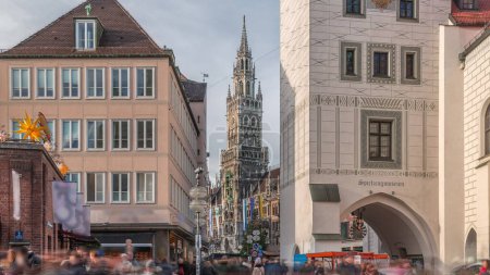 Foto de Marienplatz con el antiguo ayuntamiento de Múnich (Altes Rathaus) y el timelapse de la Puerta de Talburgo, Rathaus-Glockenspiel en el centro. Cielo nublado. Munchen-Altstadt, Baviera, Alemania. - Imagen libre de derechos