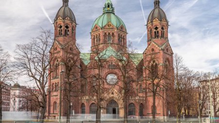 Téléchargez les photos : Église Saint-Luc (Saint-Lukas ou Lukaskirche) timelapse, la plus grande église protestante de Munich, Allemagne du Sud. Ciel nuageux et circulation dans la rue - en image libre de droit