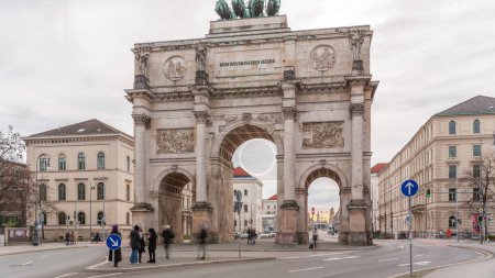 Téléchargez les photos : Le Siegestor ou Victory Gate à Munich est un arc commémoratif, couronné d'une statue de Bavière avec un lion quadriga timelapse. Trafic dans la rue autour du monument. Vue de face. Allemagne - en image libre de droit
