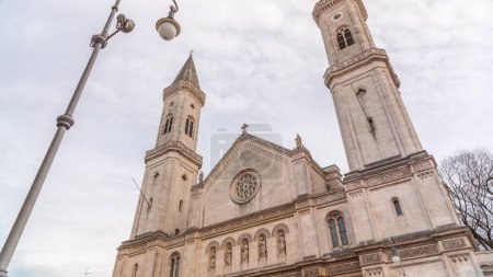 Téléchargez les photos : La paroisse catholique et l'église universitaire Saint-Louis, appelée Ludwigskirche timelapse à Munich. C'est une église monumentale de style néo-roman. Regard vers le haut avec un lampadaire. Ciel nuageux - en image libre de droit