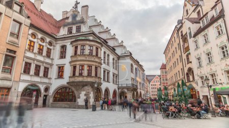 Téléchargez les photos : Paysage urbain avec des maisons de bier et des restaurants en plein air sur Platzl timelapse à Munich, Bayern, Allemagne. Zone de marche avec tables et chaises. Les gens se relaxent dans les cafés - en image libre de droit
