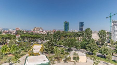 Photo for Panorama showing cityscape over Tirana with its colorful apartment buildings and skyscrapers timelapse, Tirana, Albania. Aerial view from viewpoint of pyramid with green trees and mountains - Royalty Free Image