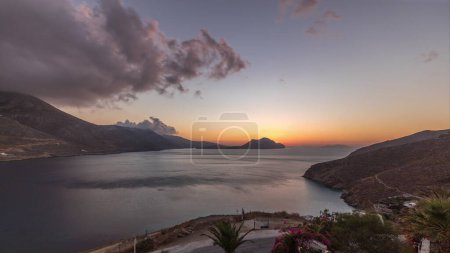 Photo for Panorama showing orange clouds during sunset on Amorgos island aerial timelapse from above. Traditional Greece - white houses on hills and turquoise sea, Cyclades - Royalty Free Image