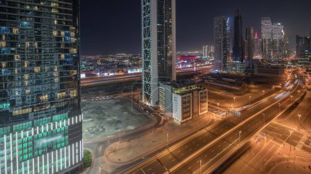 Téléchargez les photos : Panorama montrant l'horizon du quartier de la baie d'affaires avec une architecture moderne timelapse nuit d'en haut. Vue aérienne des gratte-ciel de Dubaï et des tours éclairées près de l'autoroute principale. Trafic à la croisée des chemins - en image libre de droit