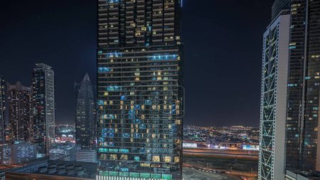 Téléchargez les photos : Panorama montrant la vue aérienne de Dubaï Downtown et Business Bay skyline avec de nombreuses tours éclairées timelapse de nuit. Zone de luxe dans la ville urbaine intelligente. gratte-ciels et immeubles de grande hauteur d'en haut - en image libre de droit