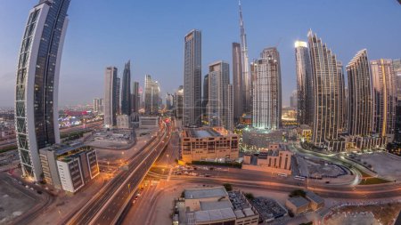 Téléchargez les photos : Vue aérienne du coucher du soleil sur Dubai Downtown skyline avec des tours de jour à nuit transition timelapse panorama. Zone d'affaires dans la ville urbaine. Soleil réfléchi par les gratte-ciel et les immeubles de grande hauteur d'en haut, EAU - en image libre de droit
