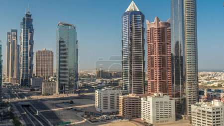 Foto de Skyline distrito de la bahía de negocios con la arquitectura moderna timelapse mañana desde arriba. Vista aérea de los rascacielos y torres de Dubái cerca de la carretera principal durante el amanecer. Tráfico en cruce y largas sombras - Imagen libre de derechos