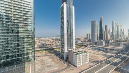 Foto de Panorama que muestra el distrito de la bahía de negocios y el horizonte del centro con un timelapse de arquitectura moderna desde arriba. Vista aérea de los rascacielos y torres de Dubái cerca de la autopista principal. Tráfico en encrucijada - Imagen libre de derechos