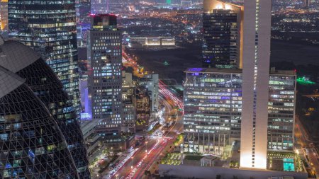 Téléchargez les photos : Vue aérienne des immeubles de grande hauteur sur la route achalandée de Dubaï timelapse de transition de jour à nuit, Émirats arabes unis. Des gratte-ciels de bureaux éclairés dans la place financière internationale d'en haut - en image libre de droit