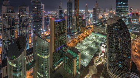 Foto de Vista del horizonte de los edificios de gran altura en Sheikh Zayed Road en Dubai aérea durante toda la noche timelapse, Emiratos Árabes Unidos. Rascacielos iluminados en el Centro Financiero Internacional desde arriba. Luces apagadas - Imagen libre de derechos