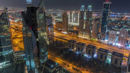 Téléchargez les photos : Bâtiments de grande hauteur sur Sheikh Zayed Road à Dubaï pendant toute la nuit timelapse, EAU. Des gratte-ciels de quartier financier d'en haut. Maisons de promenade de la ville sur un fond. Éclairage éteint - en image libre de droit